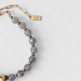 Détail du fermoir en acier inoxydable doré et du pendentif Komète Atelier sur le bracelet Kaleb en perles d’eau douce et labradorite naturelles.