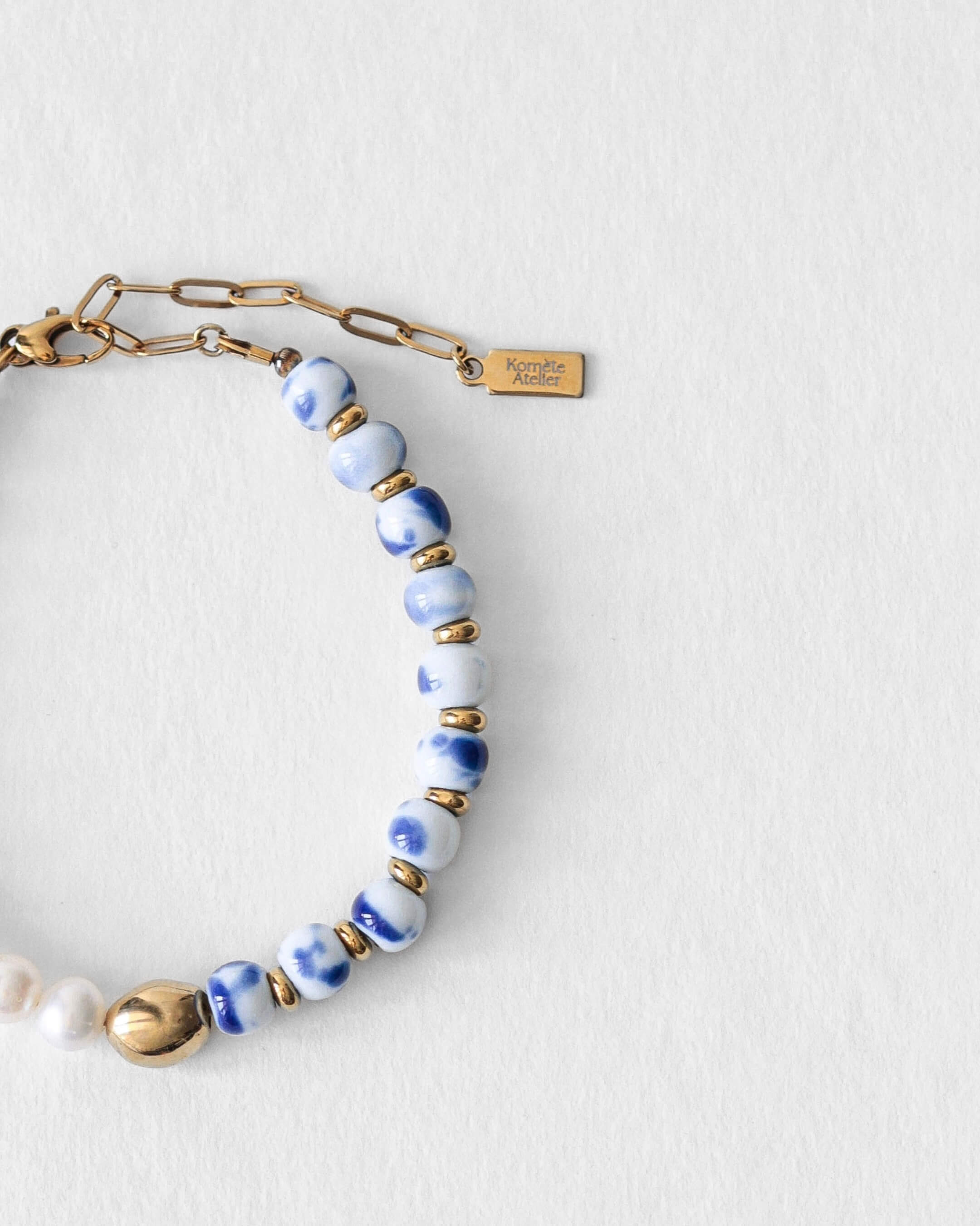 Détail du bracelet Kaleb Komète Atelier en perles de porcelaine bleue et perles d’eau douce naturelles, acier inoxydable doré à l’or 18 carats.