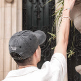 Casquette Komète Atelier gris foncé portée, logo visible à l’arrière, style décontracté