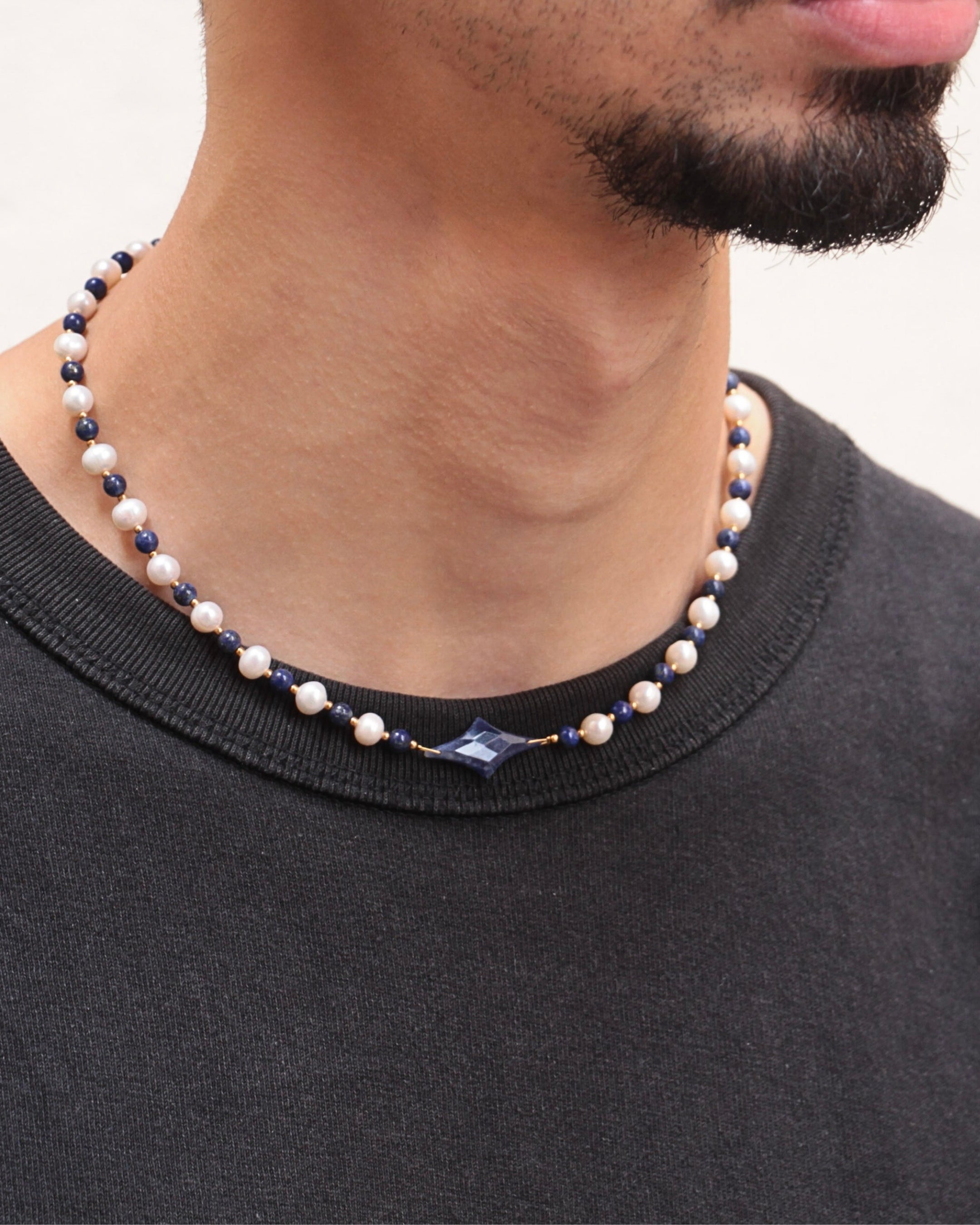 Collier Celest porté par un homme, perles de culture blanches et lapis-lazuli bleu, étoile centrale, bijou unisexe tendance.