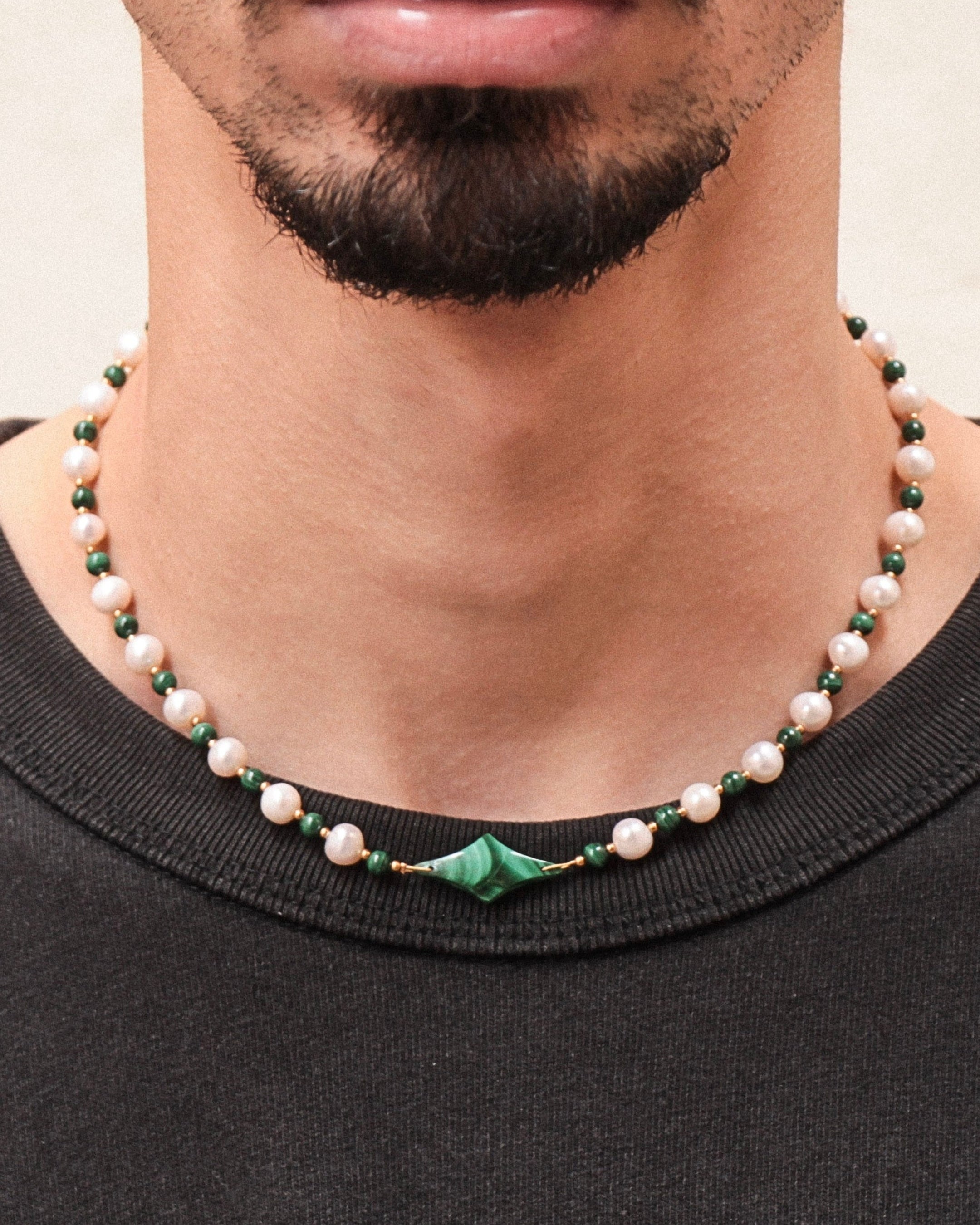 Collier Celest porté par un homme, perles de culture blanches et malachite verte, étoile centrale, bijou unisexe tendance.