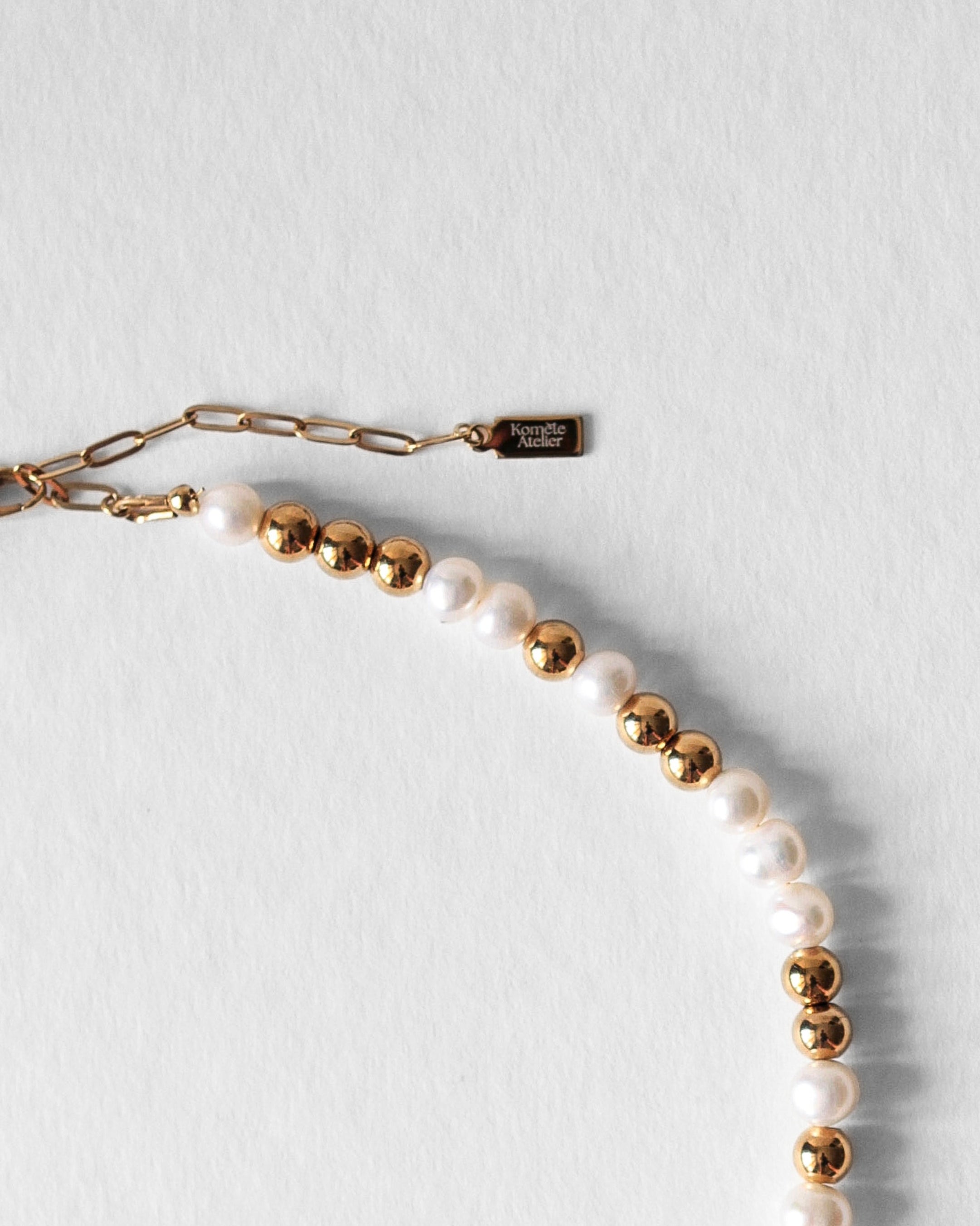Fermoir et logo signature Komète Atelier du Collier Équinox en perles d’eau douce et acier inoxydable doré.
