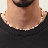 Collier Équinox perles d’eau douce et acier inoxydable doré, porté sur un homme, style moderne et raffiné.