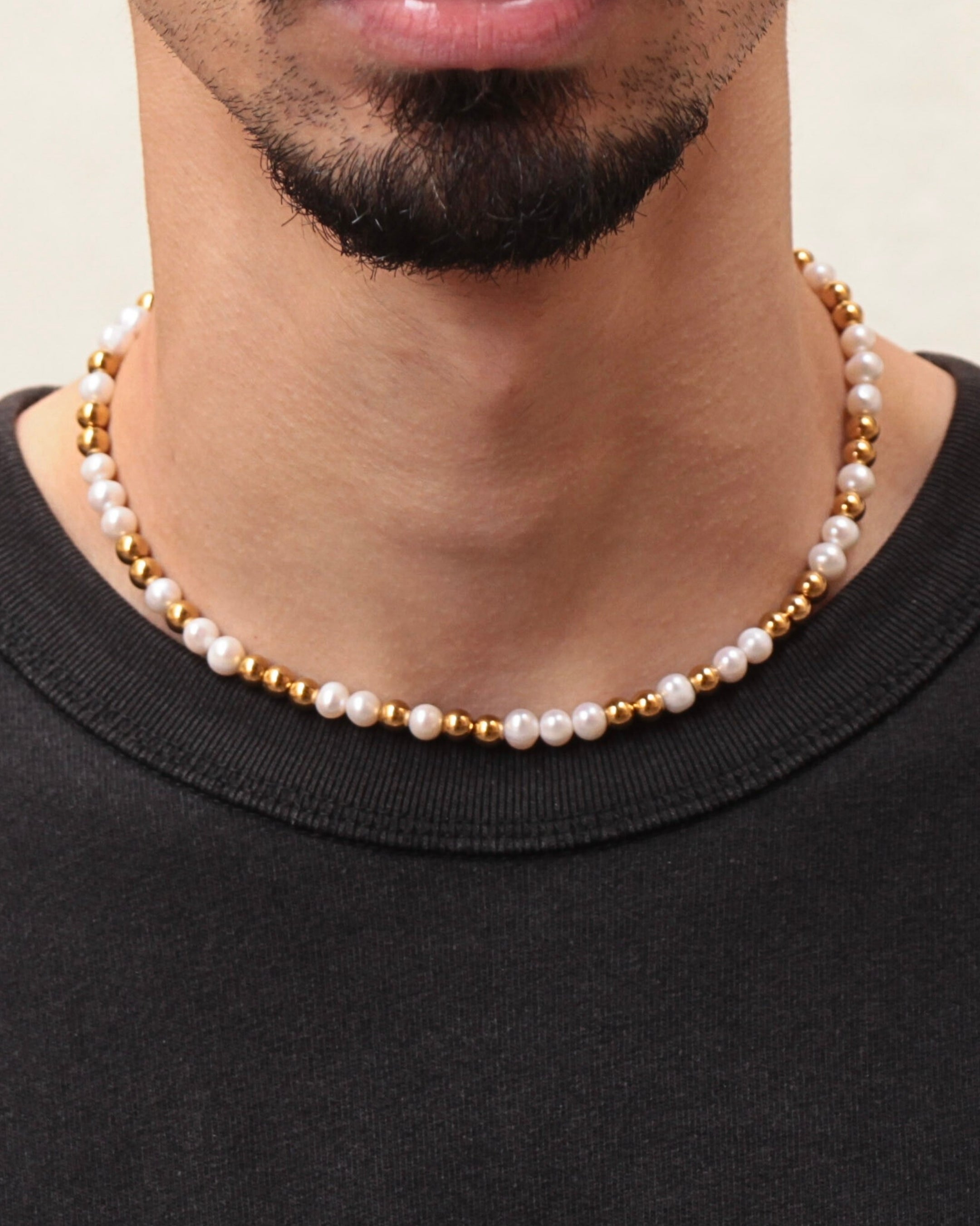 Collier Équinox perles d’eau douce et acier inoxydable doré, porté sur un homme, style moderne et raffiné.