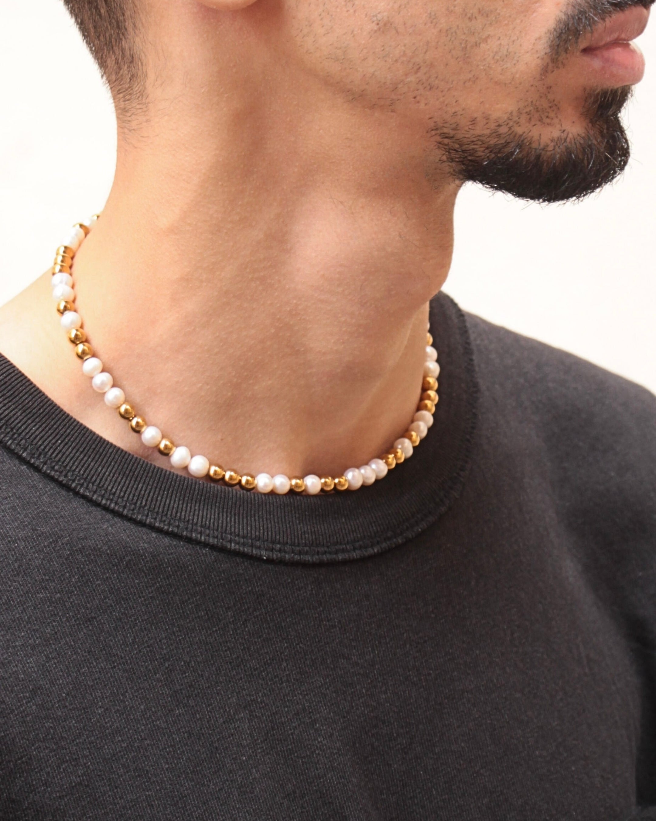 Collier Équinox en perles d’eau douce et acier inoxydable doré porté ras du cou, bijou unisexe.