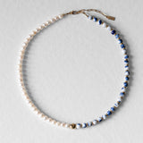 Collier Kaleb en perles de porcelaine bleue et perles d’eau douce, aussi appelées perles de culture, monté sur acier inoxydable doré. Bijou artisanal fait main Komète Atelier, collier élégant unisexe pour homme et femme en céramique et perles de culture.