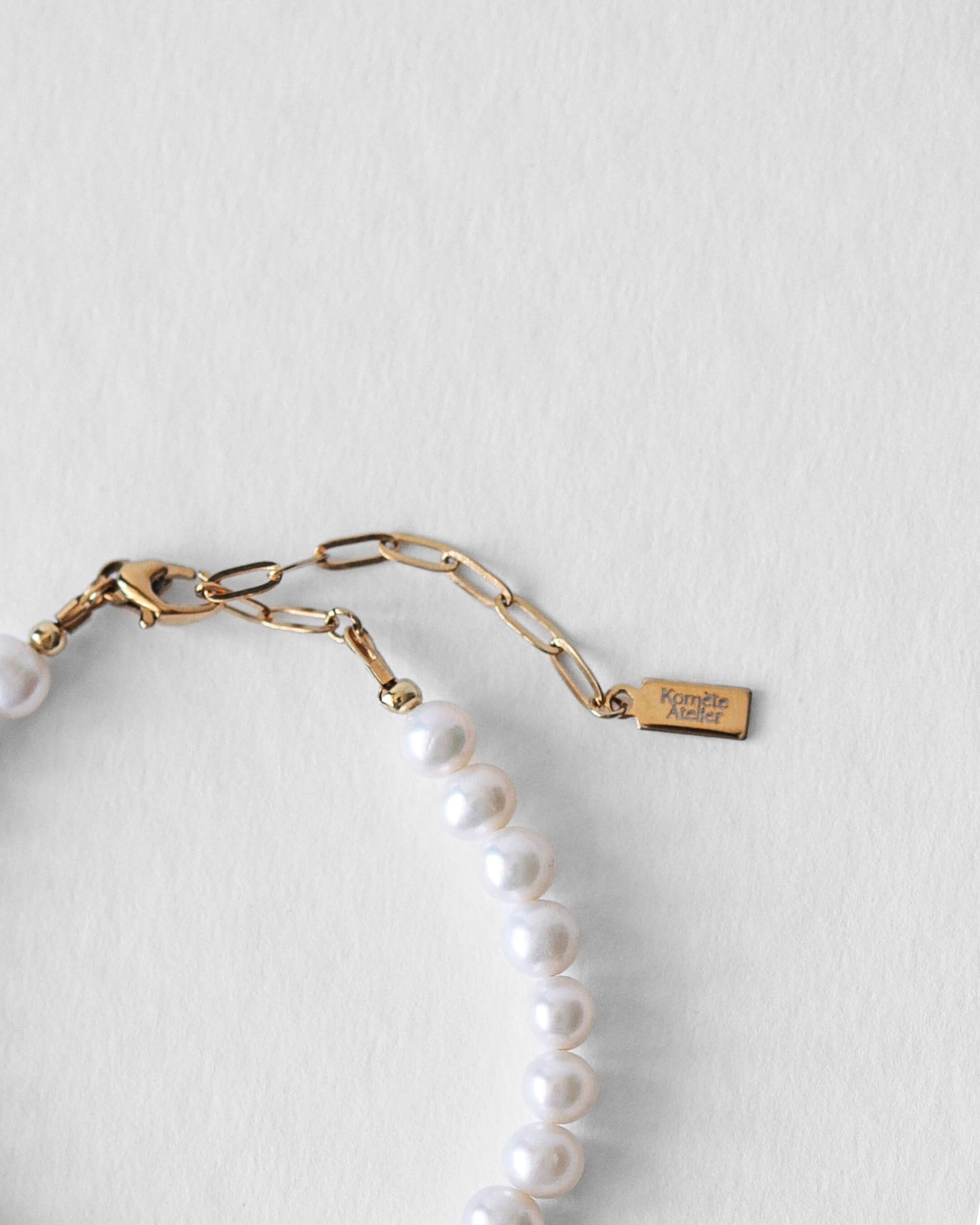 Bracelet Harry Komète Atelier avec fermoir en acier inoxydable doré à l’or 18 carats, perles d’eau douce naturelles grade AAA, bijou unisexe fait main.