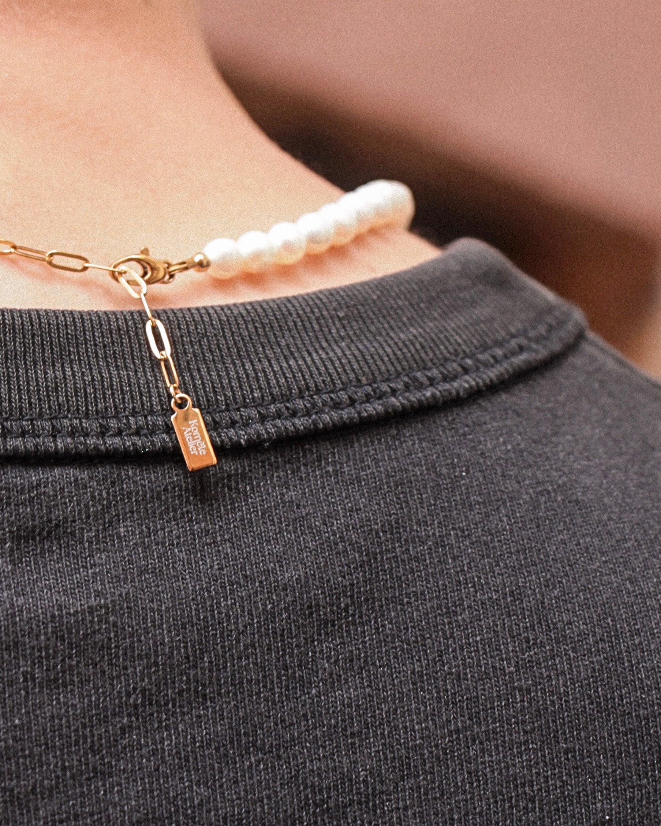 Détail du collier Harry vu de dos, fermoir en acier inoxydable doré avec logo Komète Atelier.